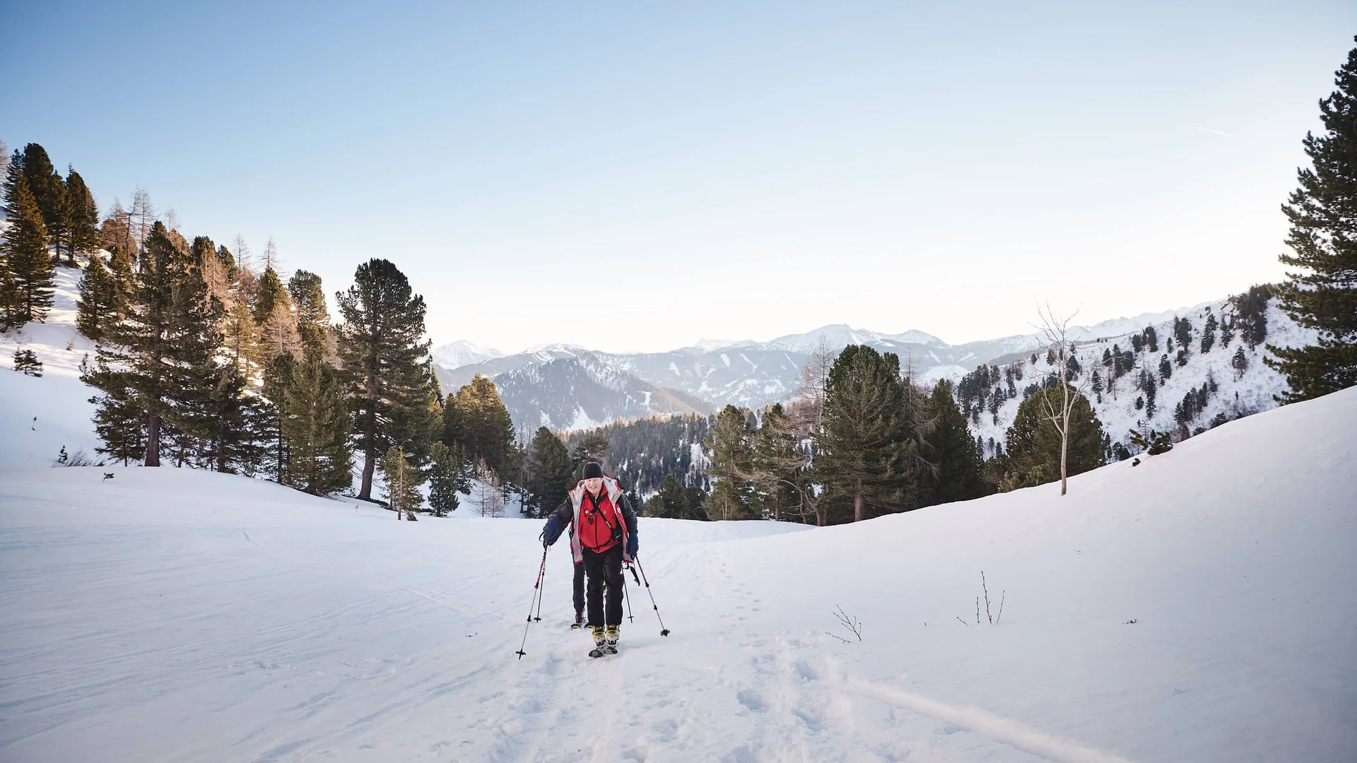 Zwei Wanderer mit Stöcken wandern durch verschneite Berglandschaft