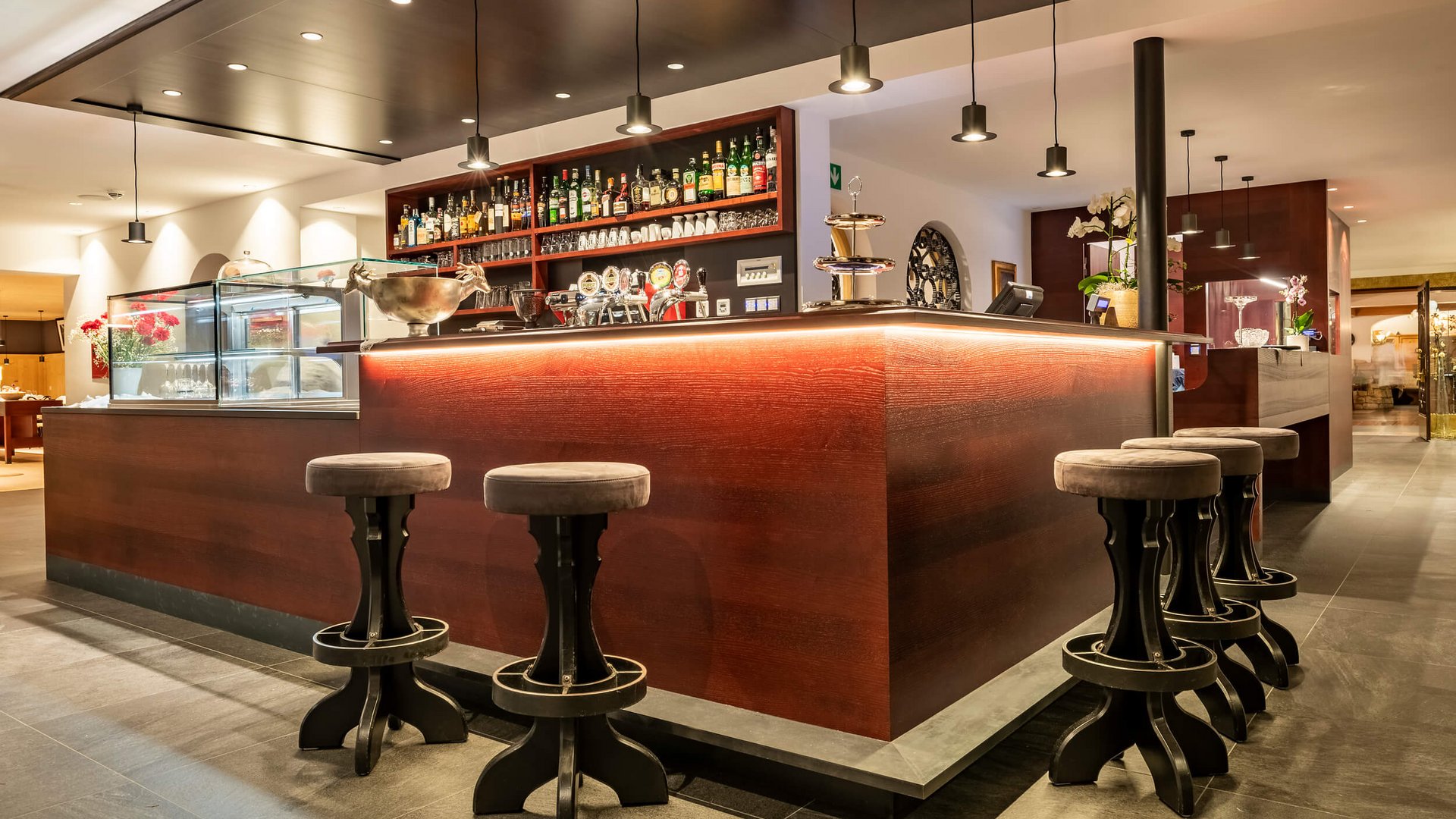 Moderner Hotelbarbereich mit leuchtendem Holztheken und Hockern