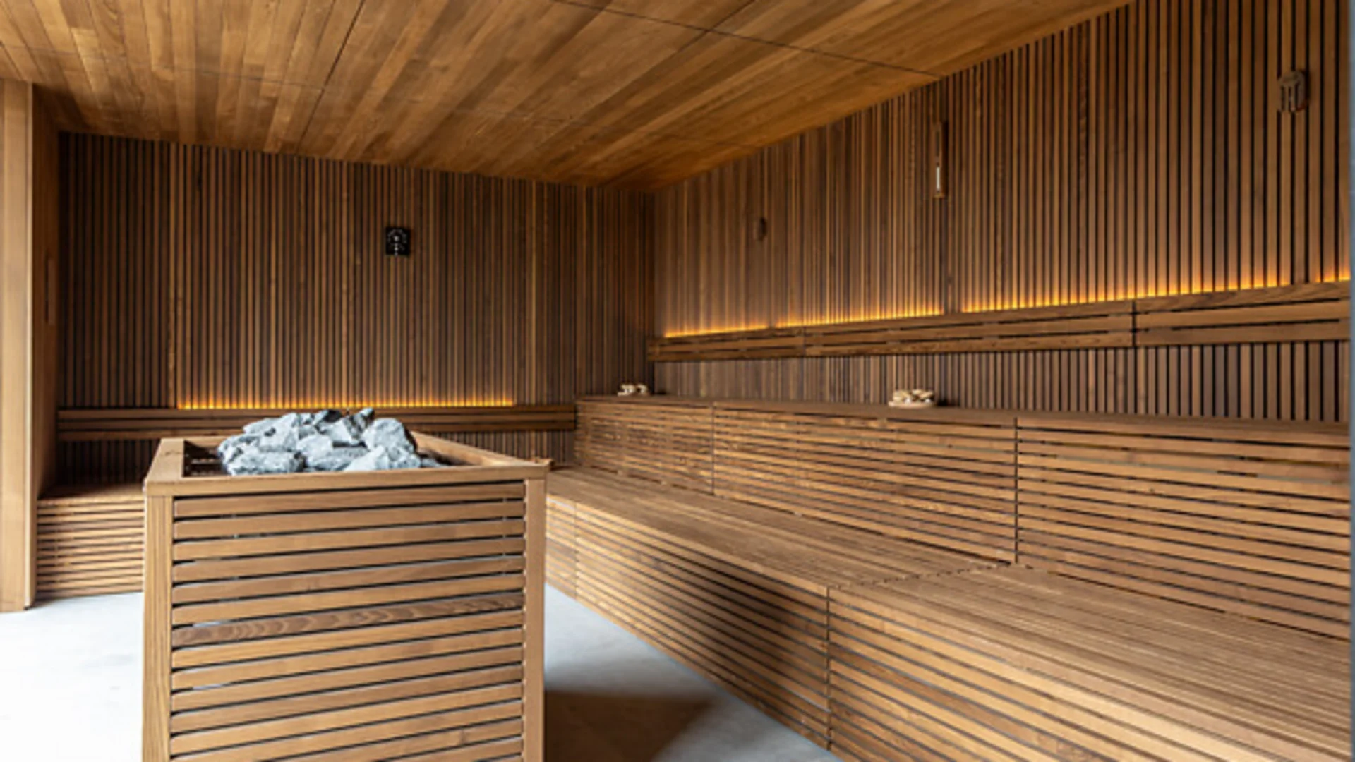 Modern sauna room with wooden panels and stones on sauna heater