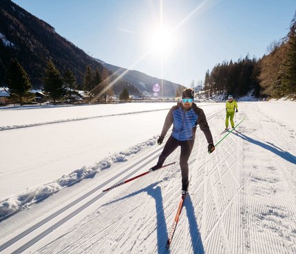 Zwei Männer beim Skilanglauf auf verschneiter Loipe bei sonnigem Wetter