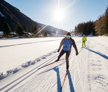 Mallnitz © Ashley Joanna Zwei Männer beim Skilanglauf auf verschneiter Loipe bei sonnigem Wetter