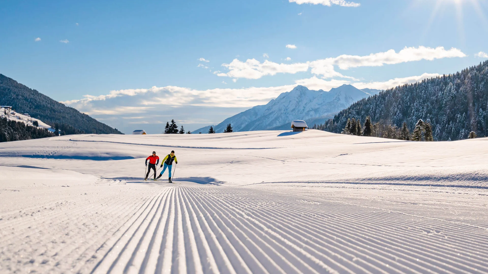 Trails & trail reports © Peter Maier Two cross-country skiers on groomed snow trail in sunny mountain landscape