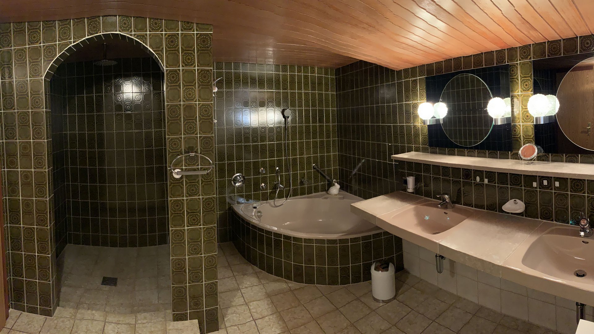 Retro bathroom with tiled walls, bathtub, shower, and double sink