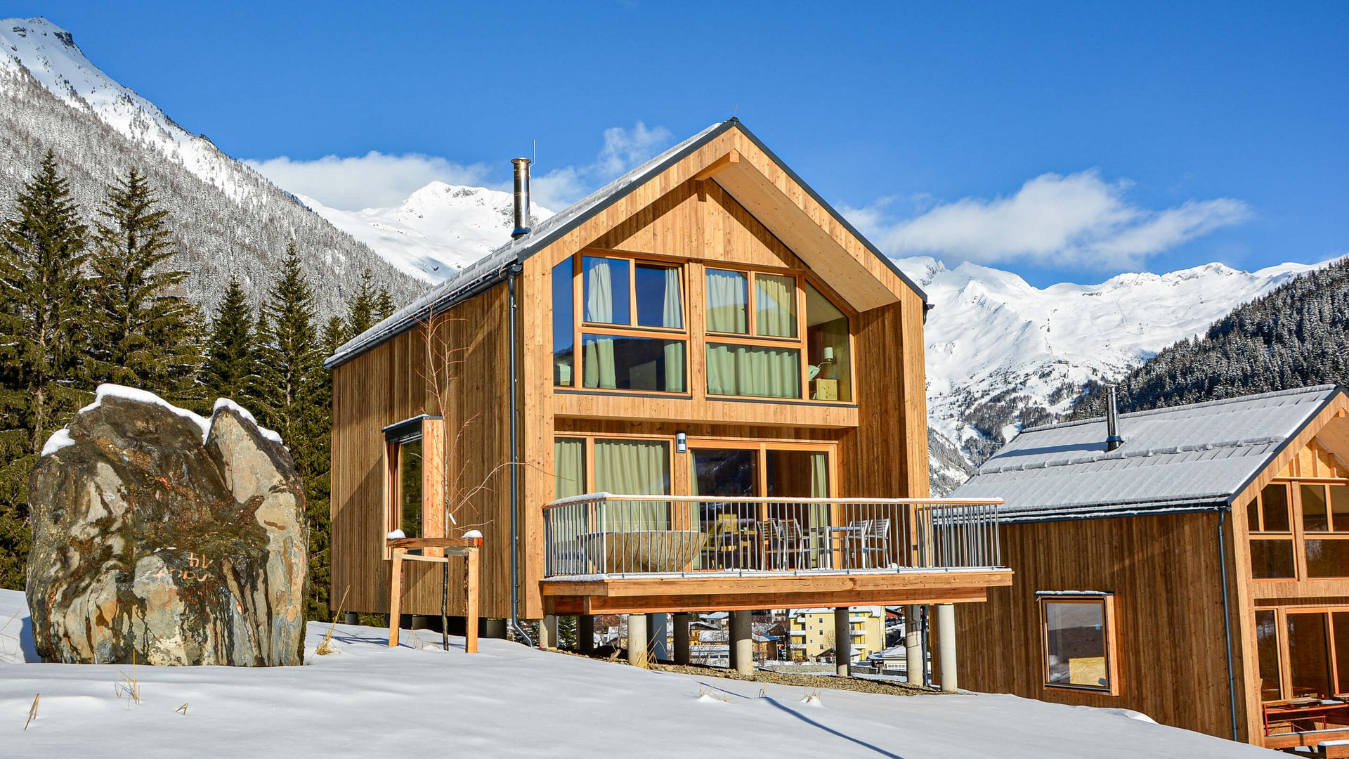 Modern wooden house in snowy mountain landscape under blue sky