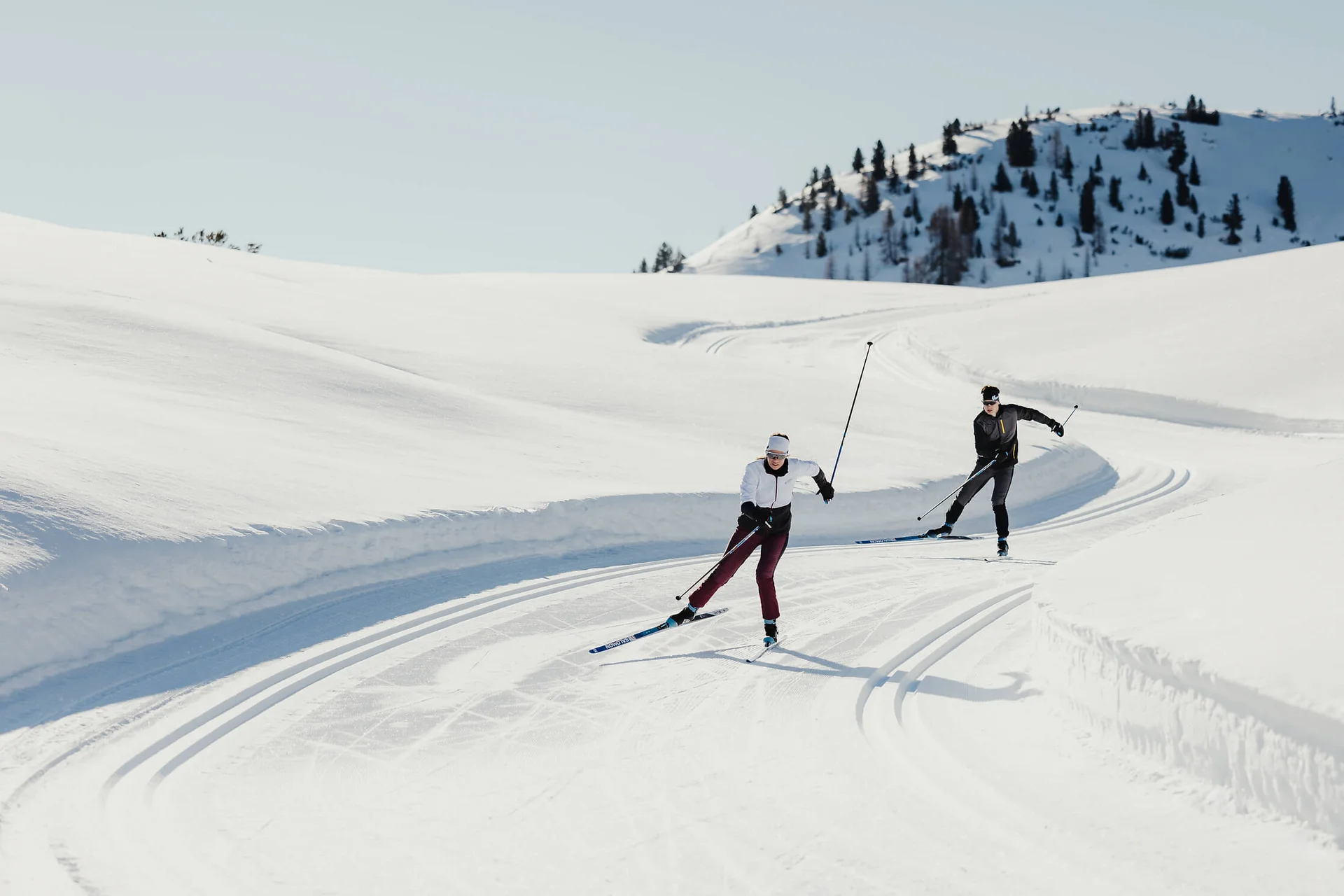 Langlauf Urlaub © Alex Moling Zwei Personen beim Langlaufen auf verschneiter Bergstrecke unter klarem Himmel