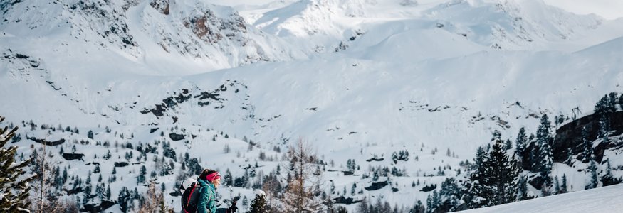 Frau wandert mit Schneeschuhen in verschneiter Berglandschaft