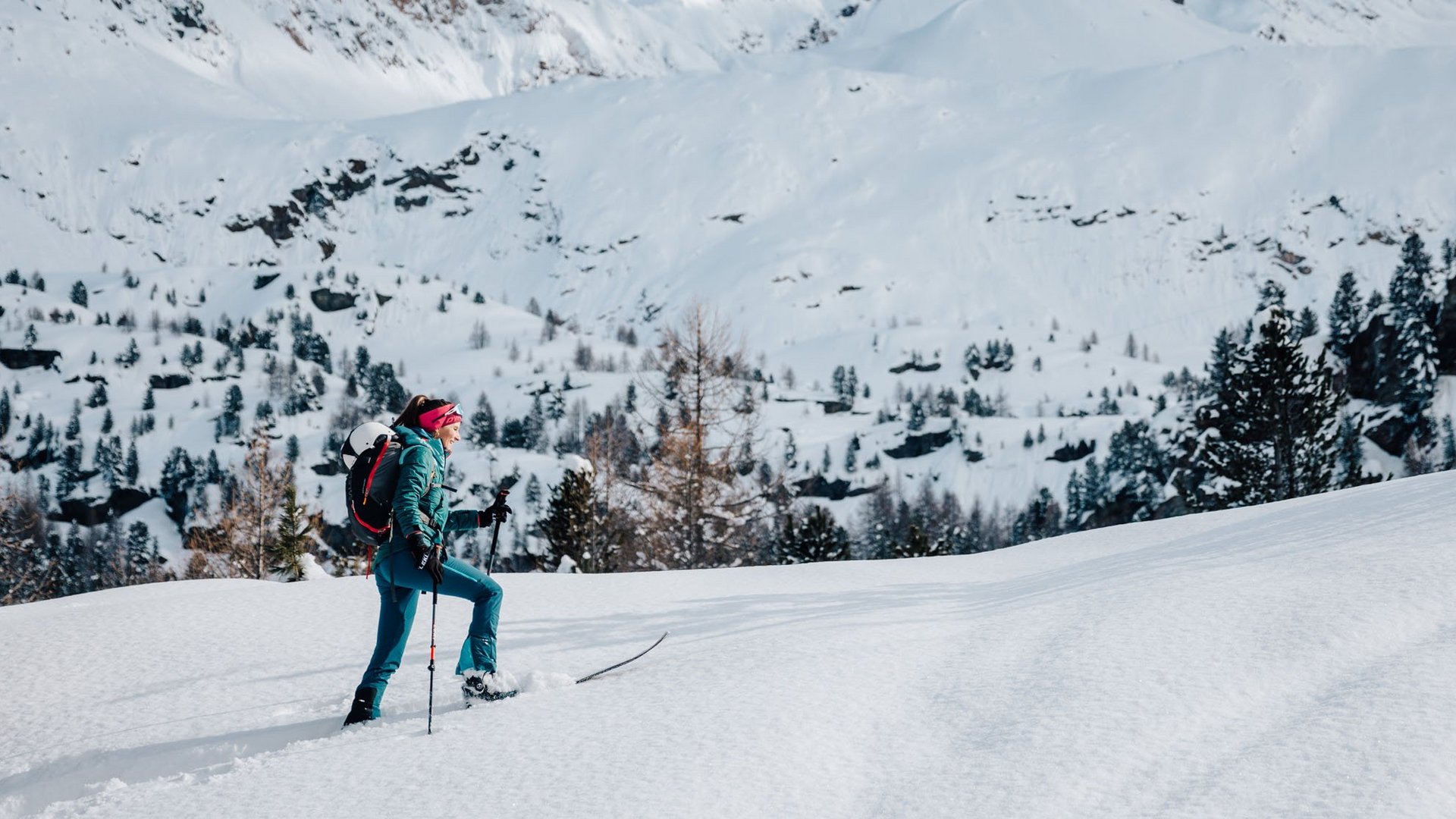 Frau wandert mit Schneeschuhen in verschneiter Berglandschaft