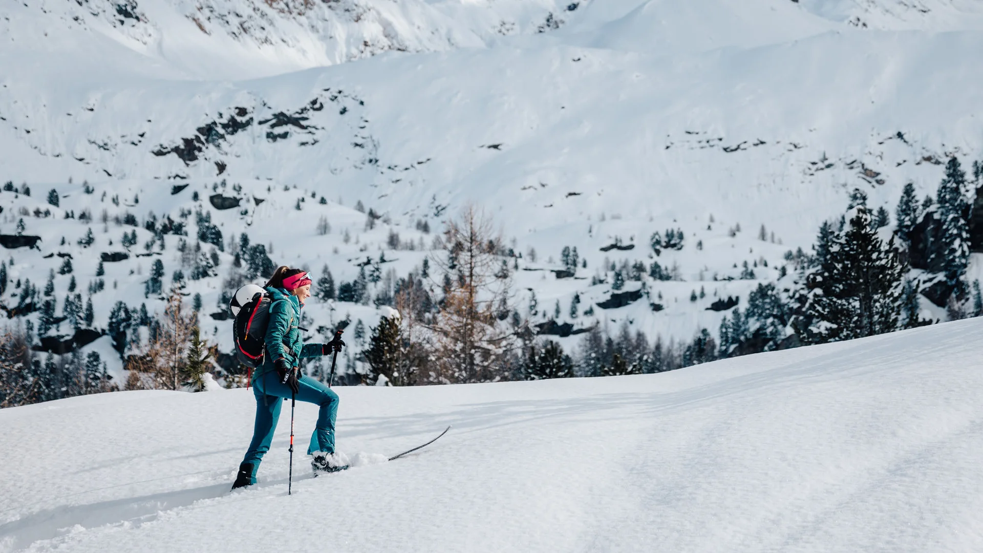 Frau wandert mit Schneeschuhen in verschneiter Berglandschaft