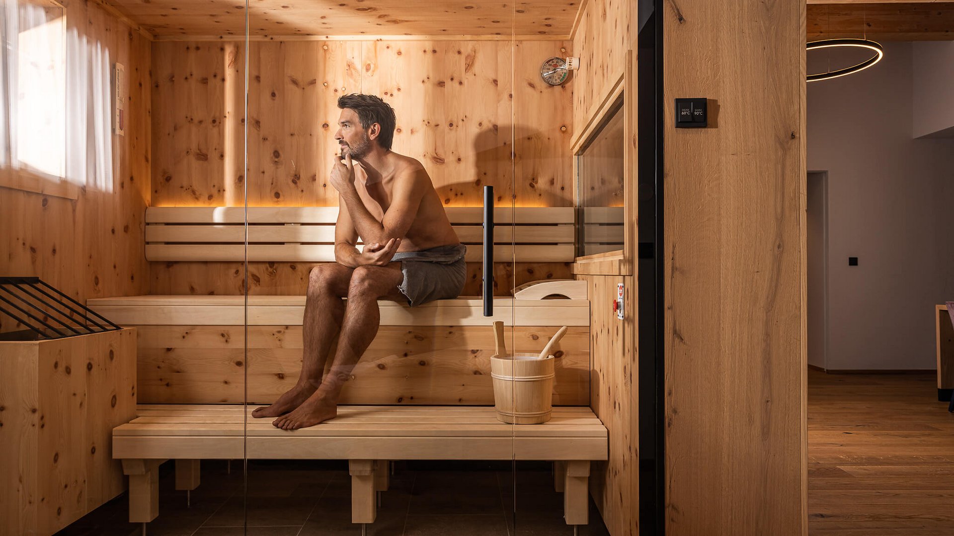 Man relaxing in a wooden sauna, sitting thoughtfully on the bench
