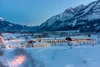 Sammelanfragen © Martin Lugger Verschneite Häuser im Tal vor beleuchteten Bergen bei Dämmerung