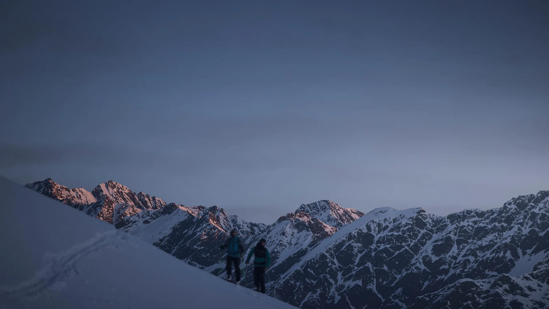 Skitouren Urlaub in Ratschings © Ratschings Tourismus - Manuel Kottersteger Zwei Wanderer auf schneebedecktem Berg mit Alpen im Hintergrund bei Dämmerung