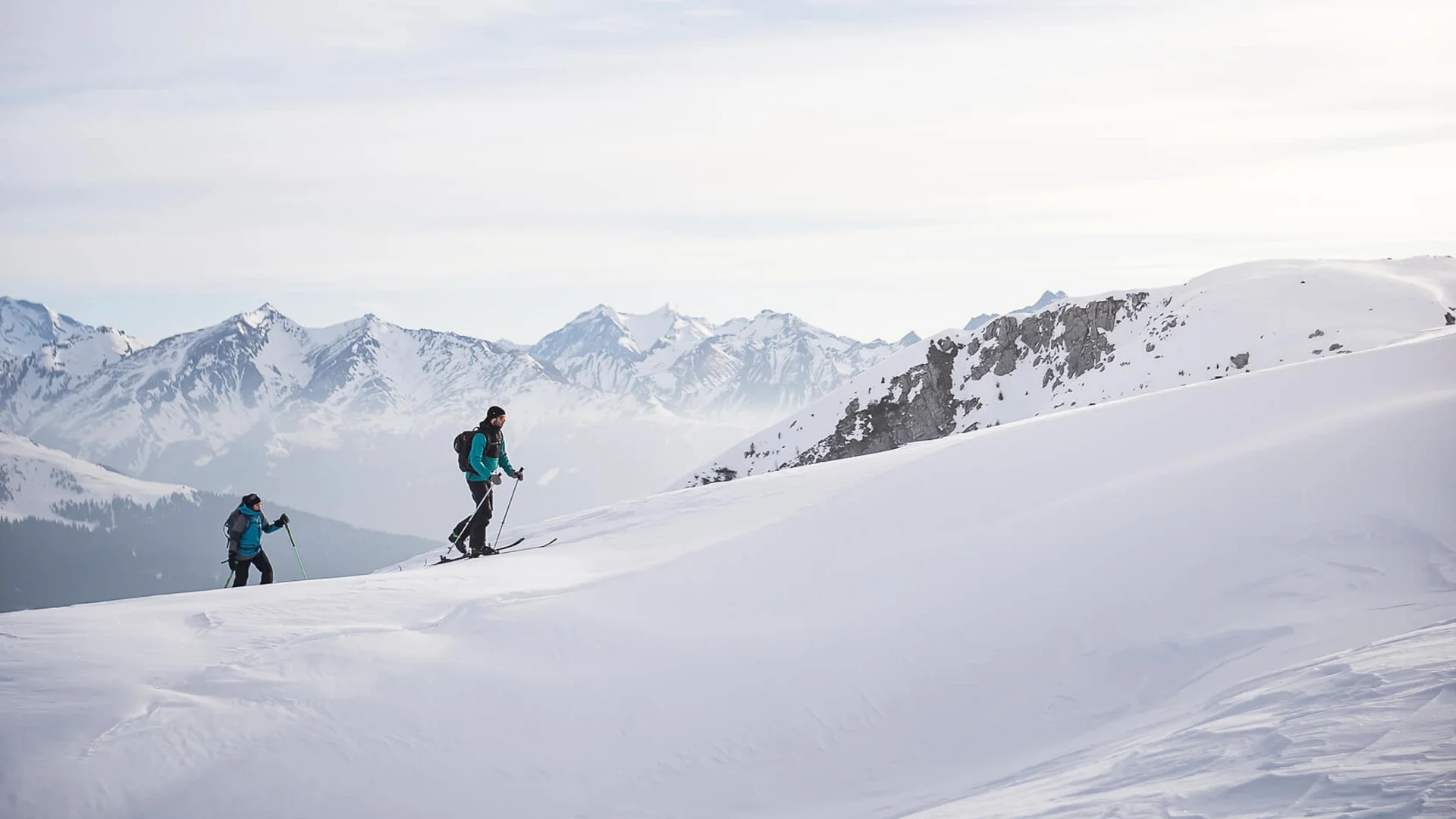 Skitouren Urlaub in Ratschings © Ratschings Tourismus - Manuel Kottersteger Zwei Skifahrer steigen einen schneebedeckten Berg mit Bergen im Hintergrund hinauf