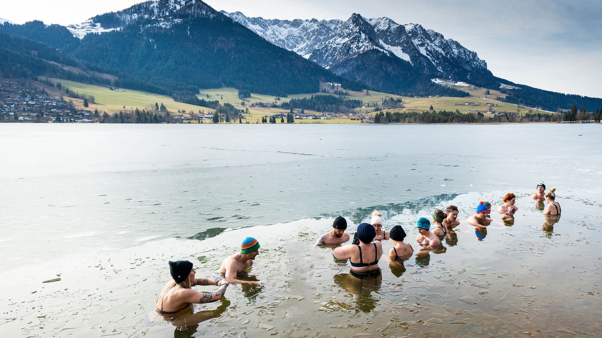 Group bathing in icy lake near snowy mountains
