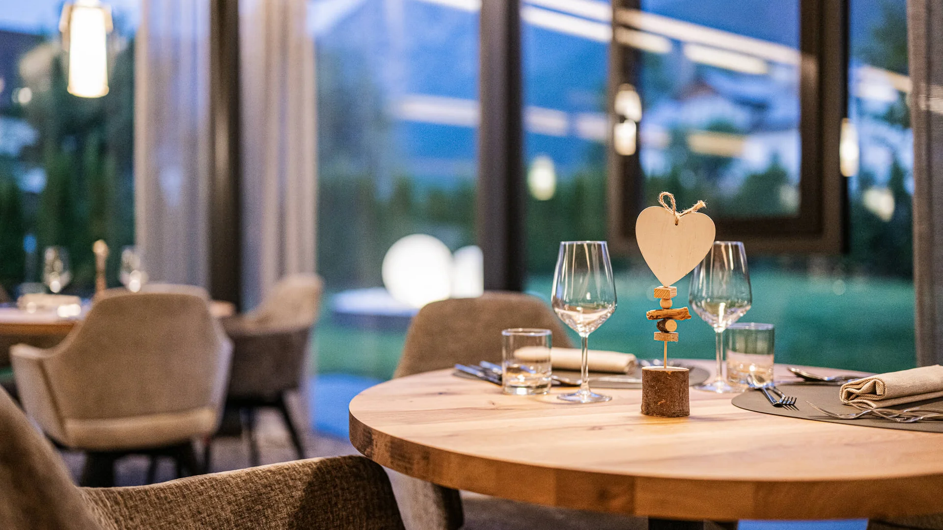 Round wooden table with decoration and glasses in a cozy restaurant
