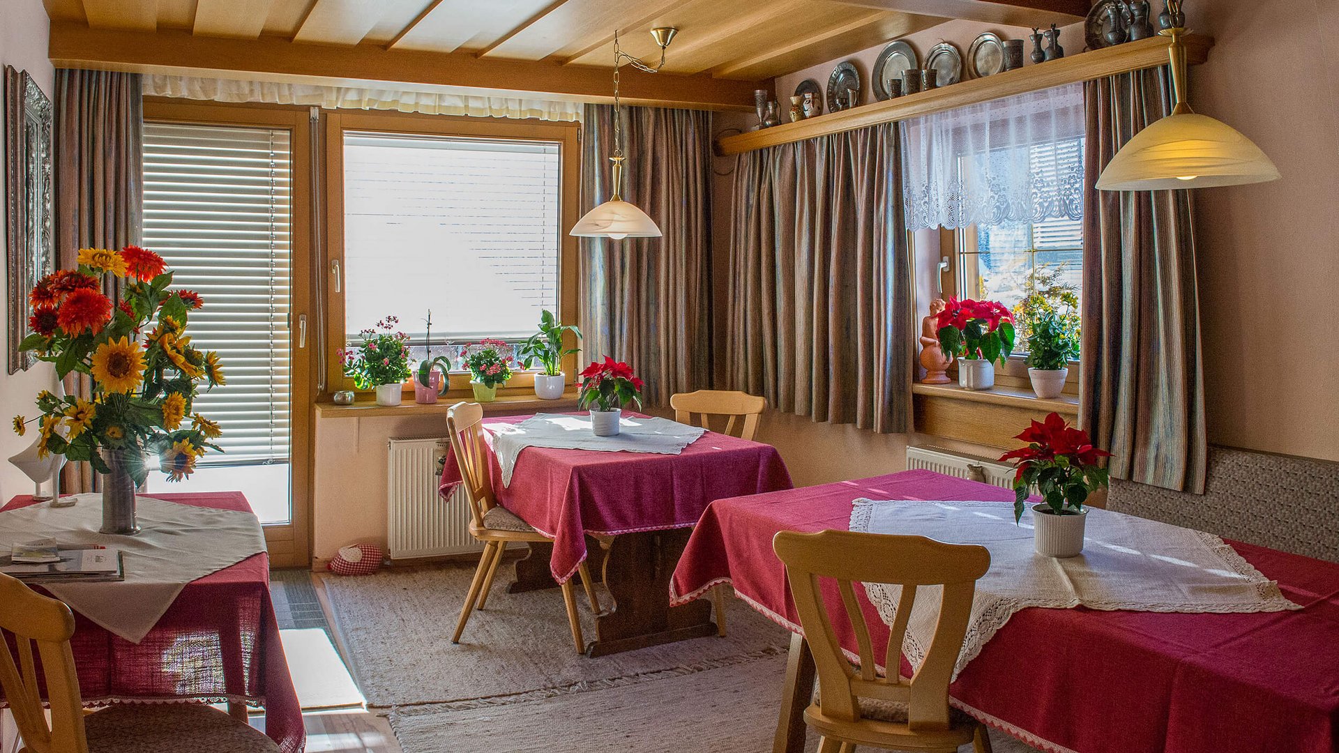 Cozy dining room with red tablecloths and flowers on the tables