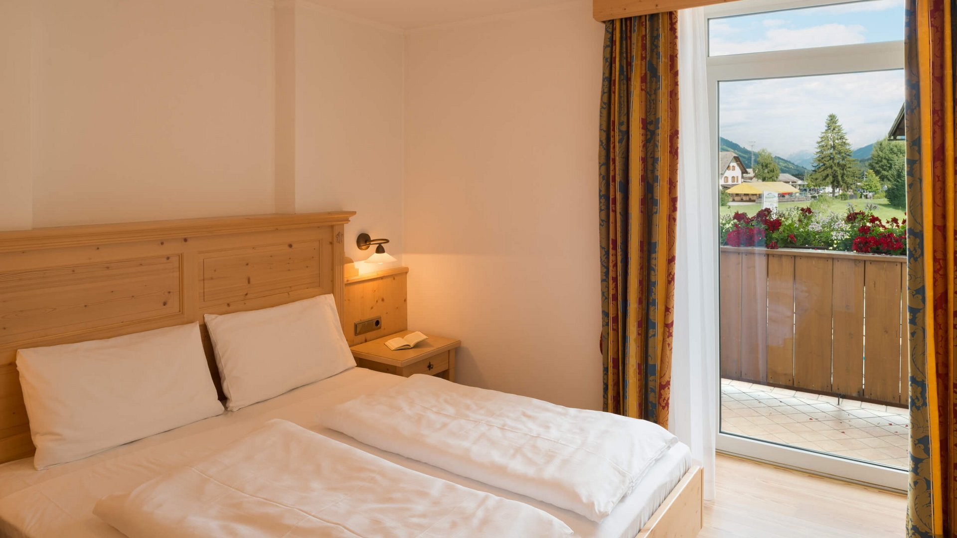 Gemütliches Hotelzimmer mit Doppelbett und Blick auf Balkon und Landschaft