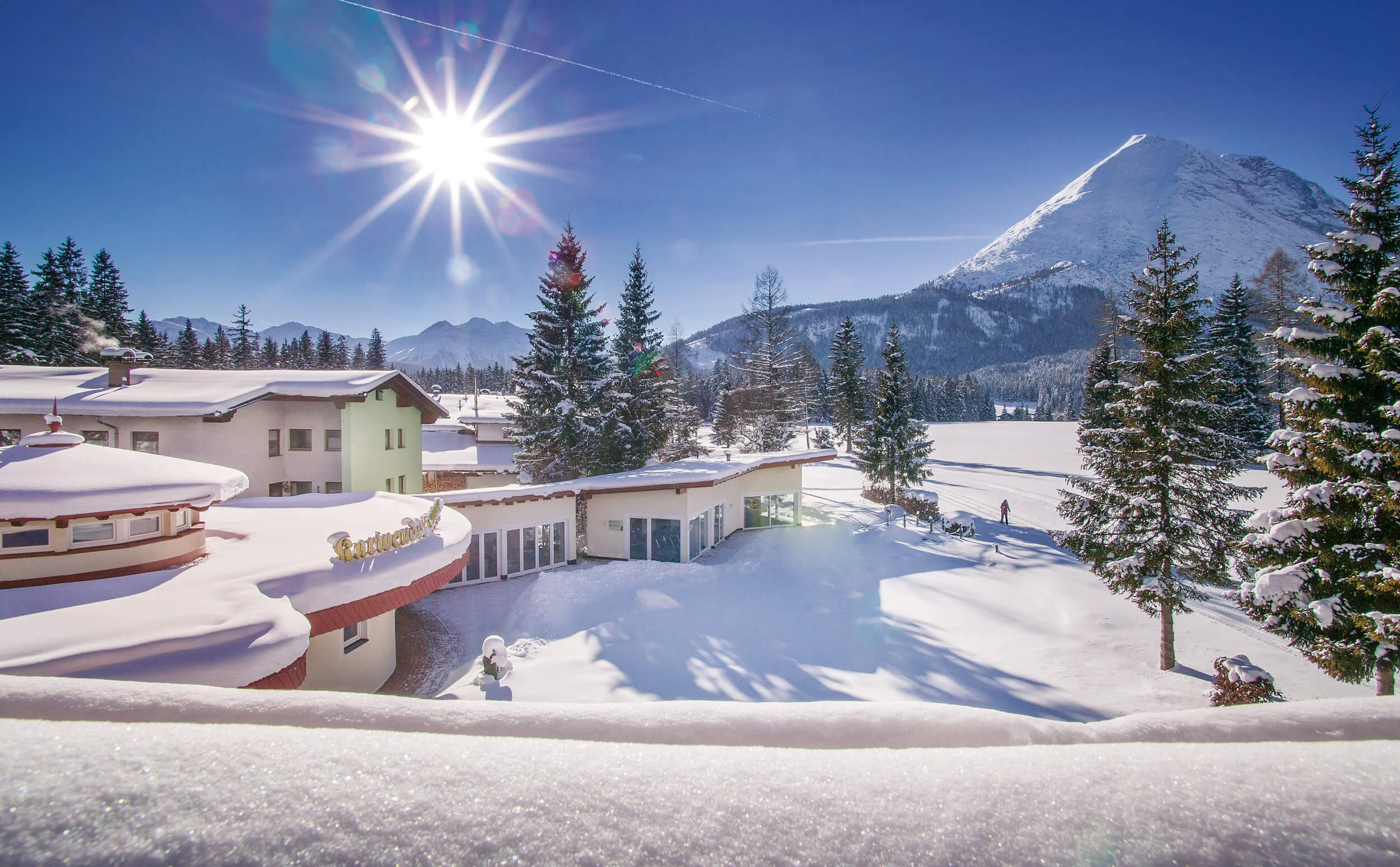 Winter-Schnuppertage im Alpenhotel Karwendel © Hotel Karwendel Bernhard Rödlach BetriebsGmbH Schneebedeckte Häuser und Bäume vor sonnigem Bergpanorama