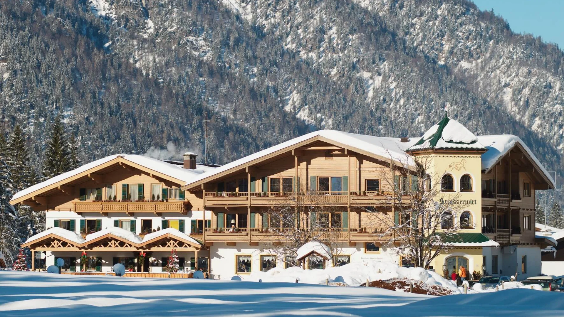 Schneebedecktes altes Holzhaus vor bewaldetem Berg im Winter