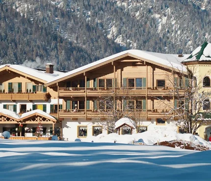 Landhotel Strasserwirt © Reinhold Glaser Schneebedecktes altes Holzhaus vor bewaldetem Berg im Winter
