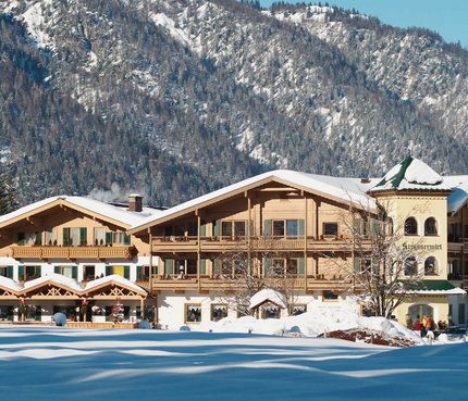 Landhotel Strasserwirt © Reinhold Glaser Schneebedecktes altes Holzhaus vor bewaldetem Berg im Winter
