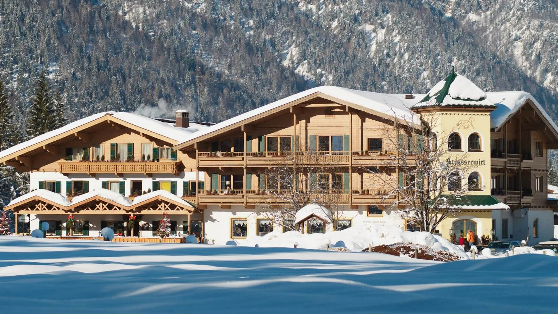 Schneebedecktes altes Holzhaus vor bewaldetem Berg im Winter