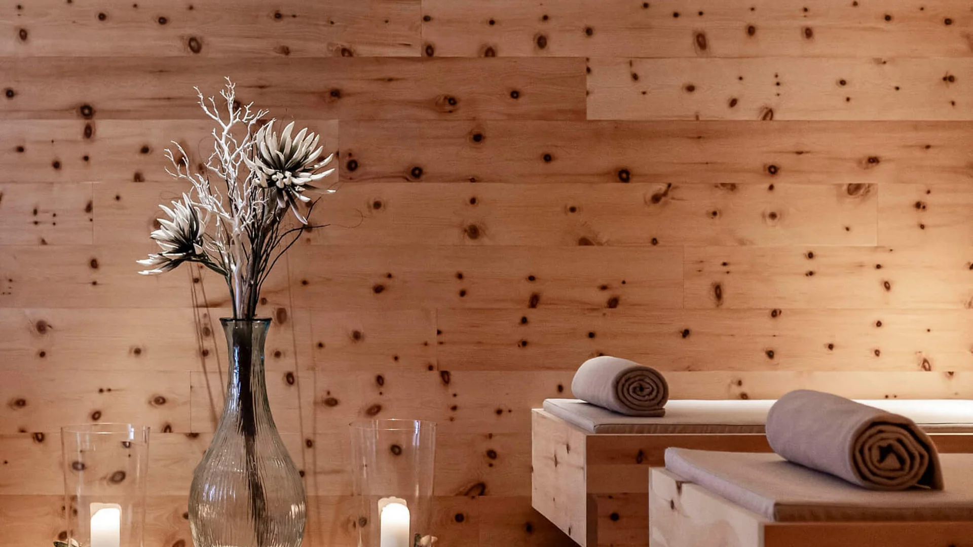 Entspannungsraum mit Holzverkleidung, Kerzenlicht und dekorativen Blumen