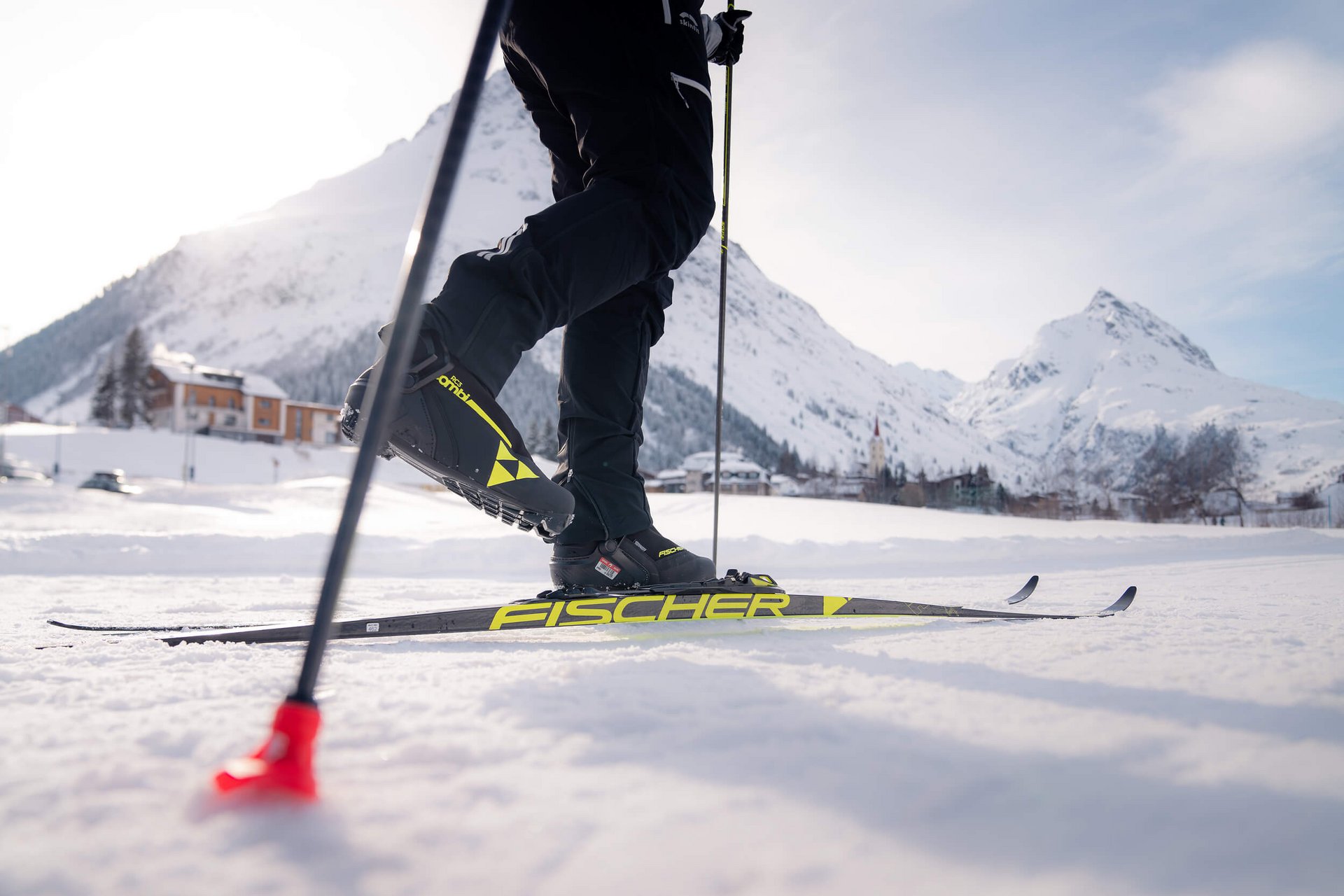 Person beim Langlaufen auf verschneiter Berglandschaft mit Skiern und Stöcken