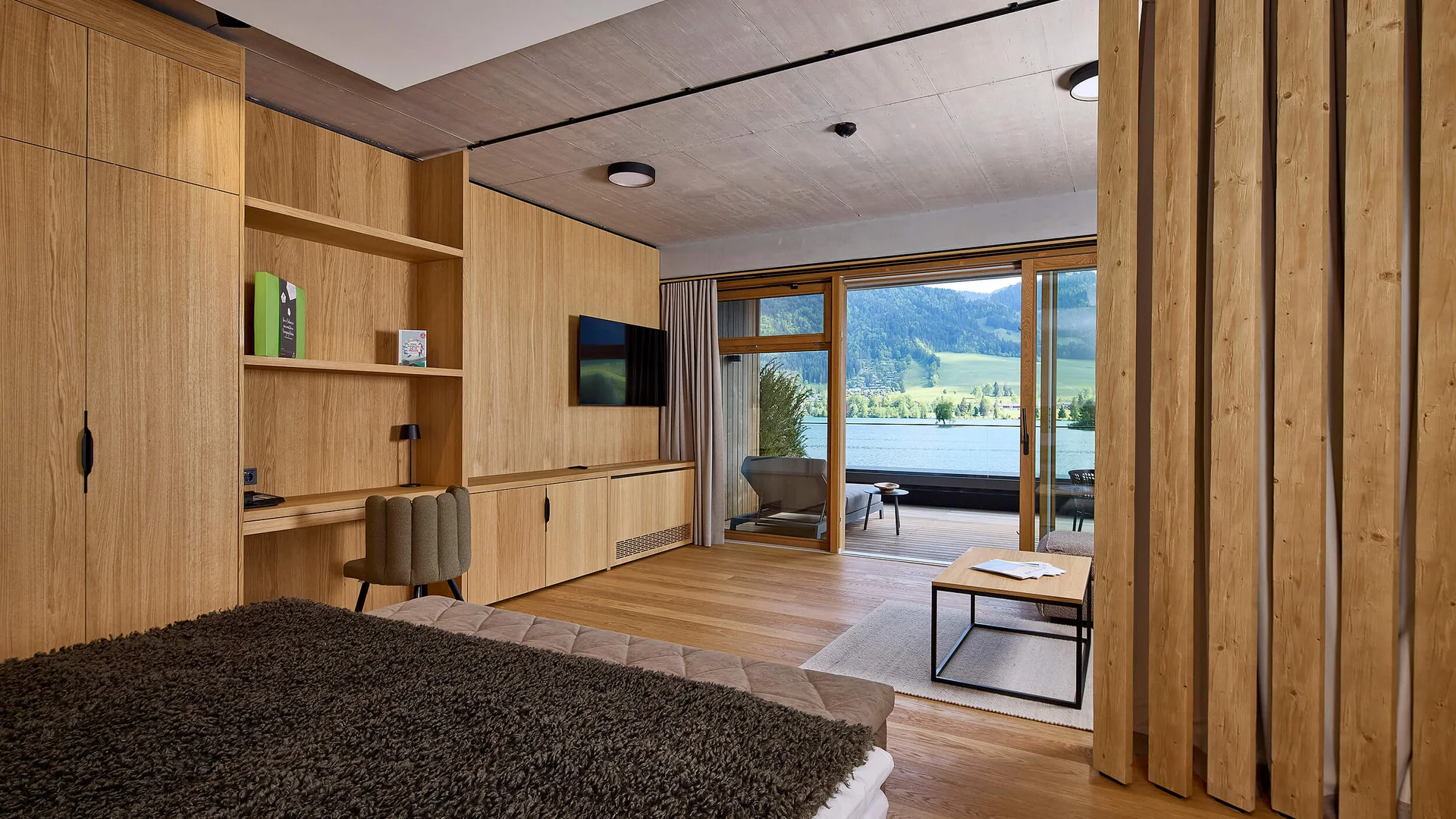 Modernes Hotelzimmer mit Holzmöbeln und Blick auf See und Berge