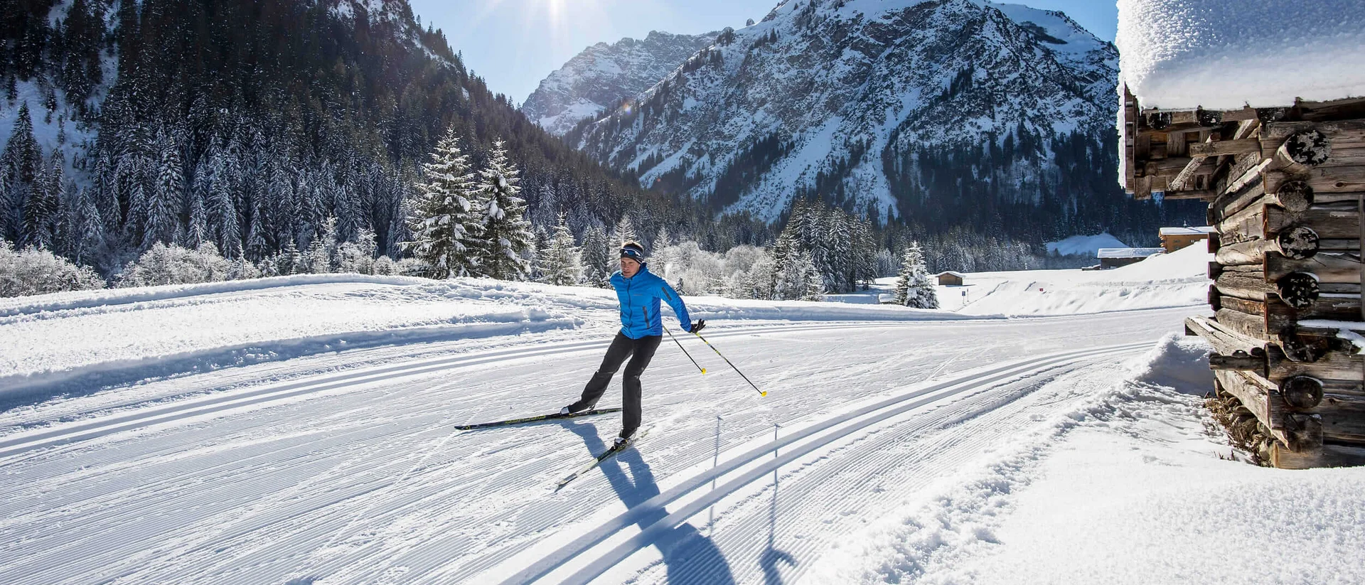 Kleinwalsertal © Dominik Berchtold Langläufer auf einer verschneiten Loipe vor schneebedeckten Bergen