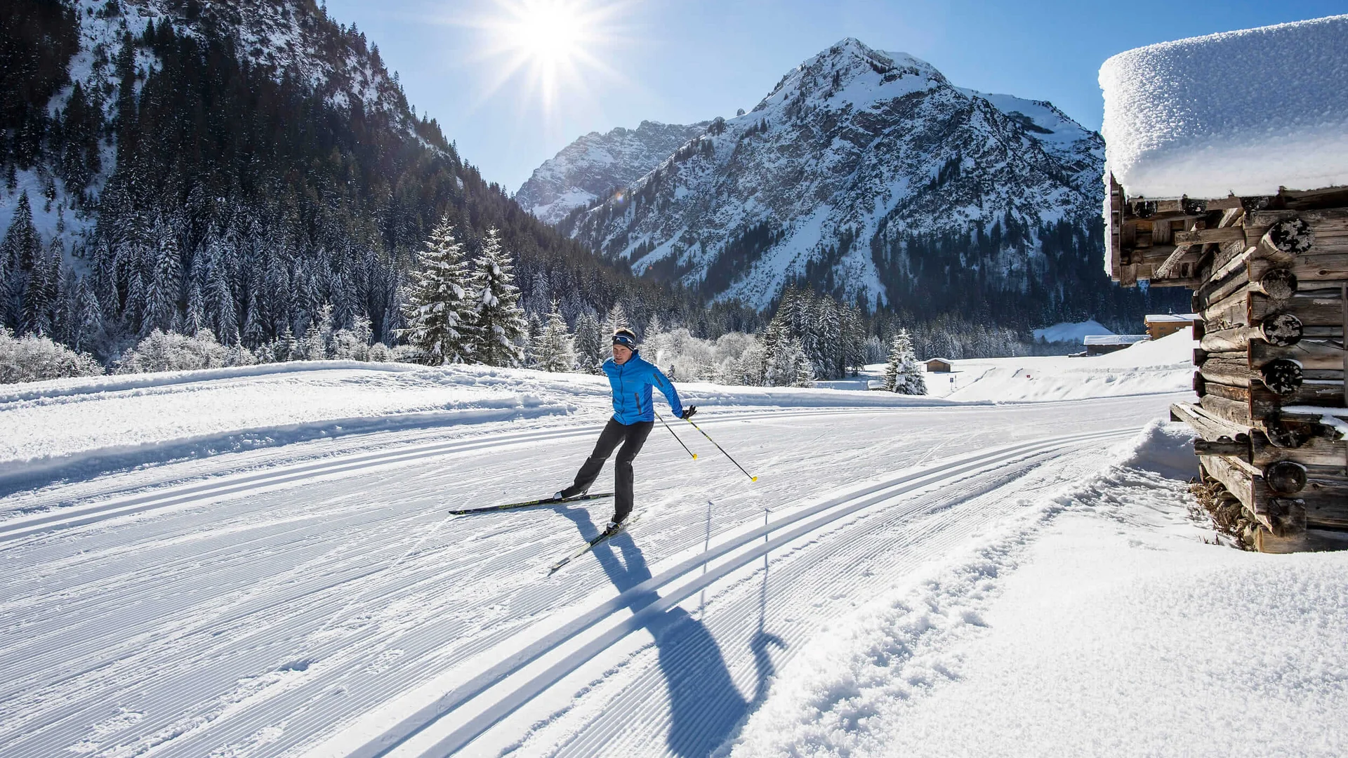 Winterurlaub in Vorarlberg © Dominik Berchtold Langläufer auf einer verschneiten Loipe vor schneebedeckten Bergen