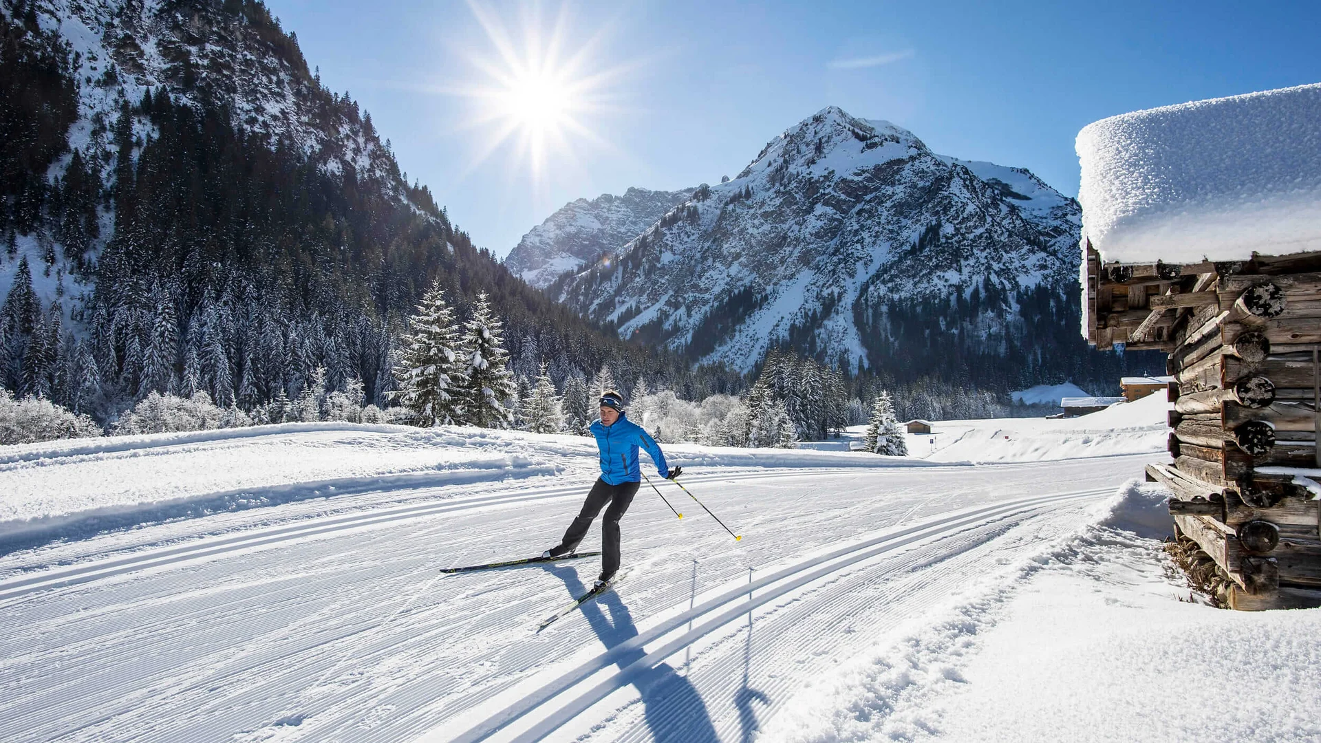 Langlauf Urlaub im Kleinwalsertal © Dominik Berchtold Langläufer auf einer verschneiten Loipe vor schneebedeckten Bergen