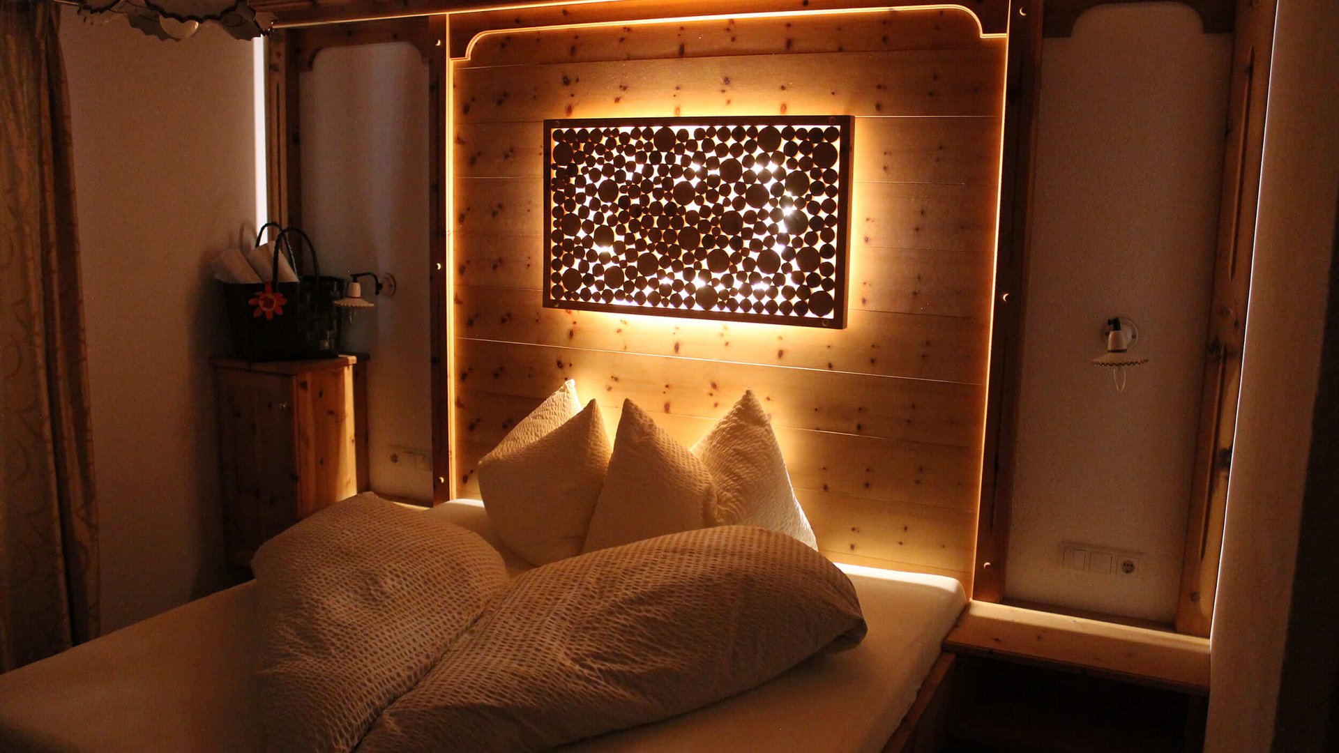 Gemütliches Schlafzimmer mit warmem Holz und indirekter Beleuchtung über dem Bett
