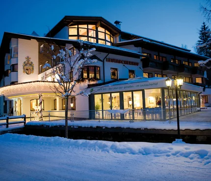 Leutascherhof Hotel im Winter mit Schnee und Beleuchtung bei Abenddämmerung