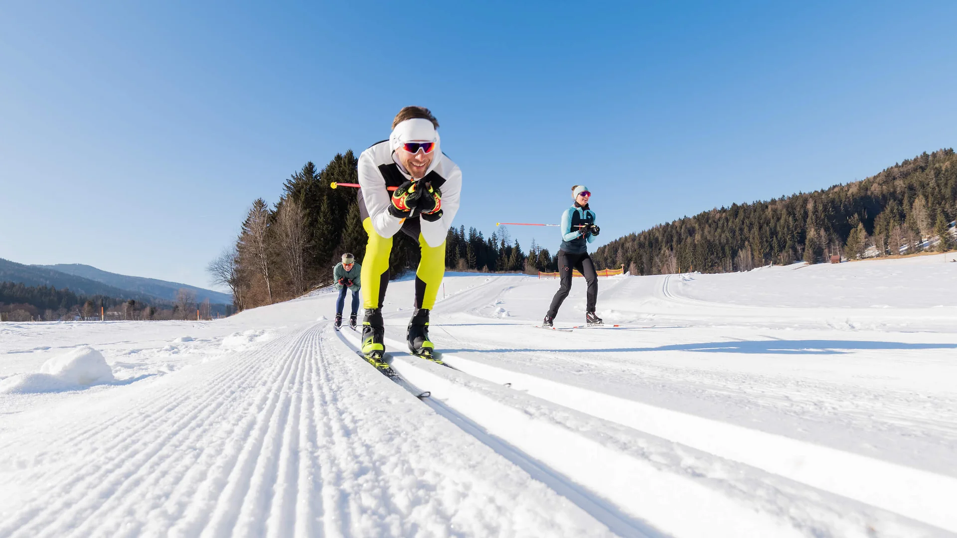 Langlauf Urlaub im Salzburger Lungau © Salzburger Lungau Drei Personen beim Langlaufen auf präparierter Schneestrecke bei Sonnenschein