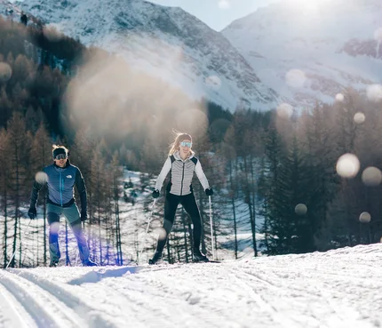 Passeiertal © Tourismusverein Passeiertal - Benjamin Pfitscher Zwei Personen beim Langlaufen vor verschneiten Bergen und Wald