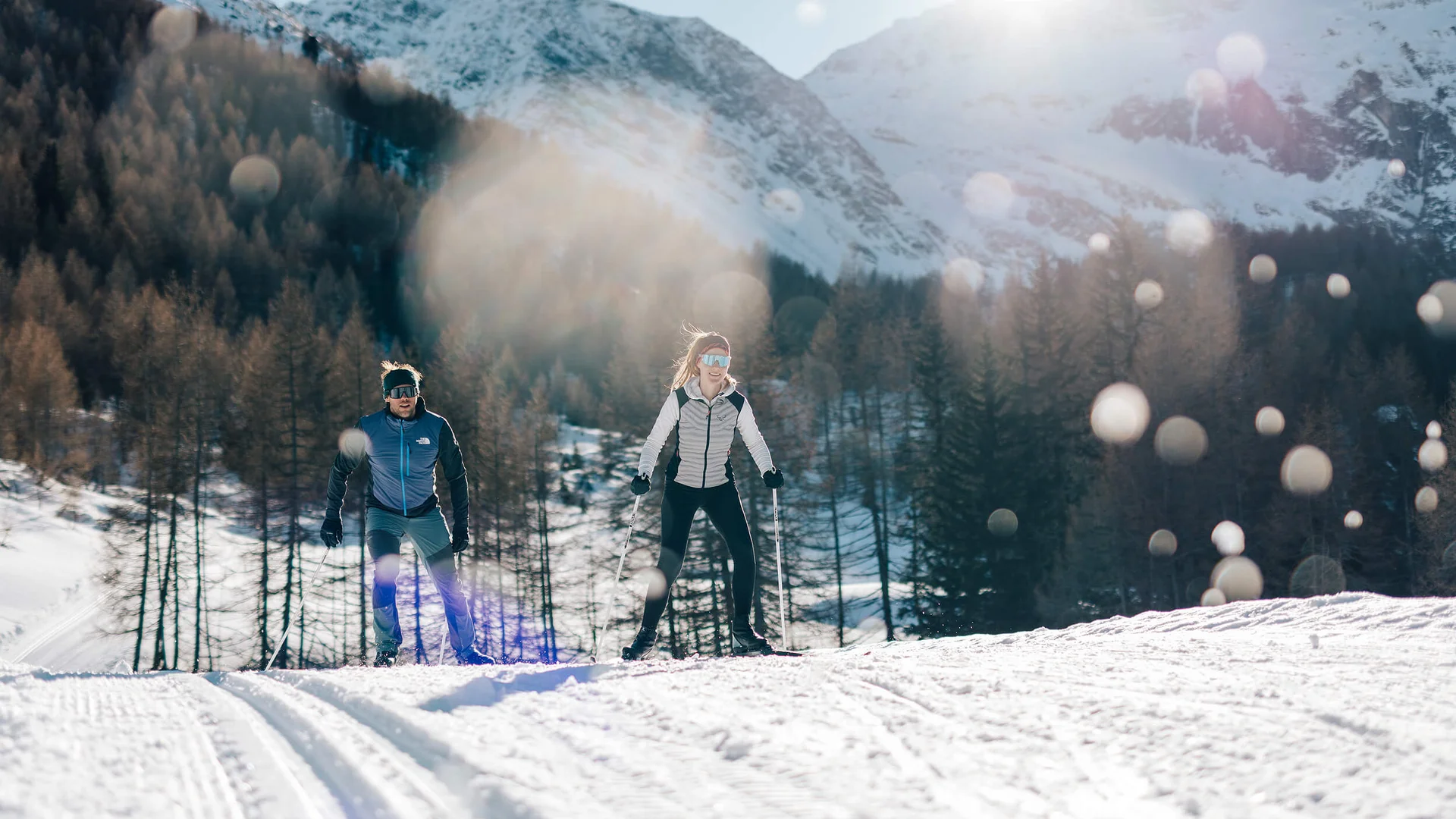 Langlauf Urlaub im Passeiertal © Tourismusverein Passeiertal - Benjamin Pfitscher Zwei Personen beim Langlaufen vor verschneiten Bergen und Wald