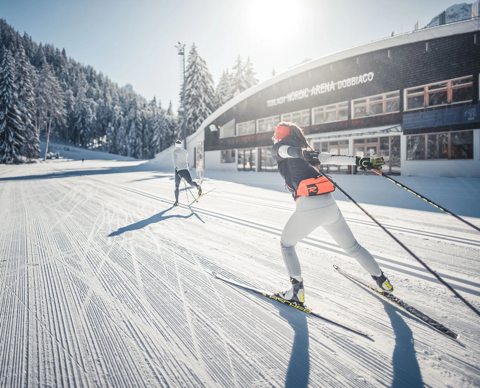 Hobby Biathlon © Kottersteger Langläufer beim Skilanglauf vor verschneiter Waldlandschaft und Gebäude