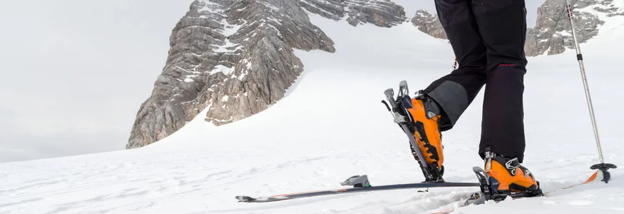 Skibergsteiger steigt mit Steigeisen und Stöcken auf verschneitem Berg auf