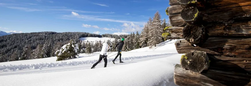 Alm-Hotel Starkenfeld Hütte ** © Alex Filz Zwei Menschen beim Langlaufski im verschneiten Wald bei klarem Himmel