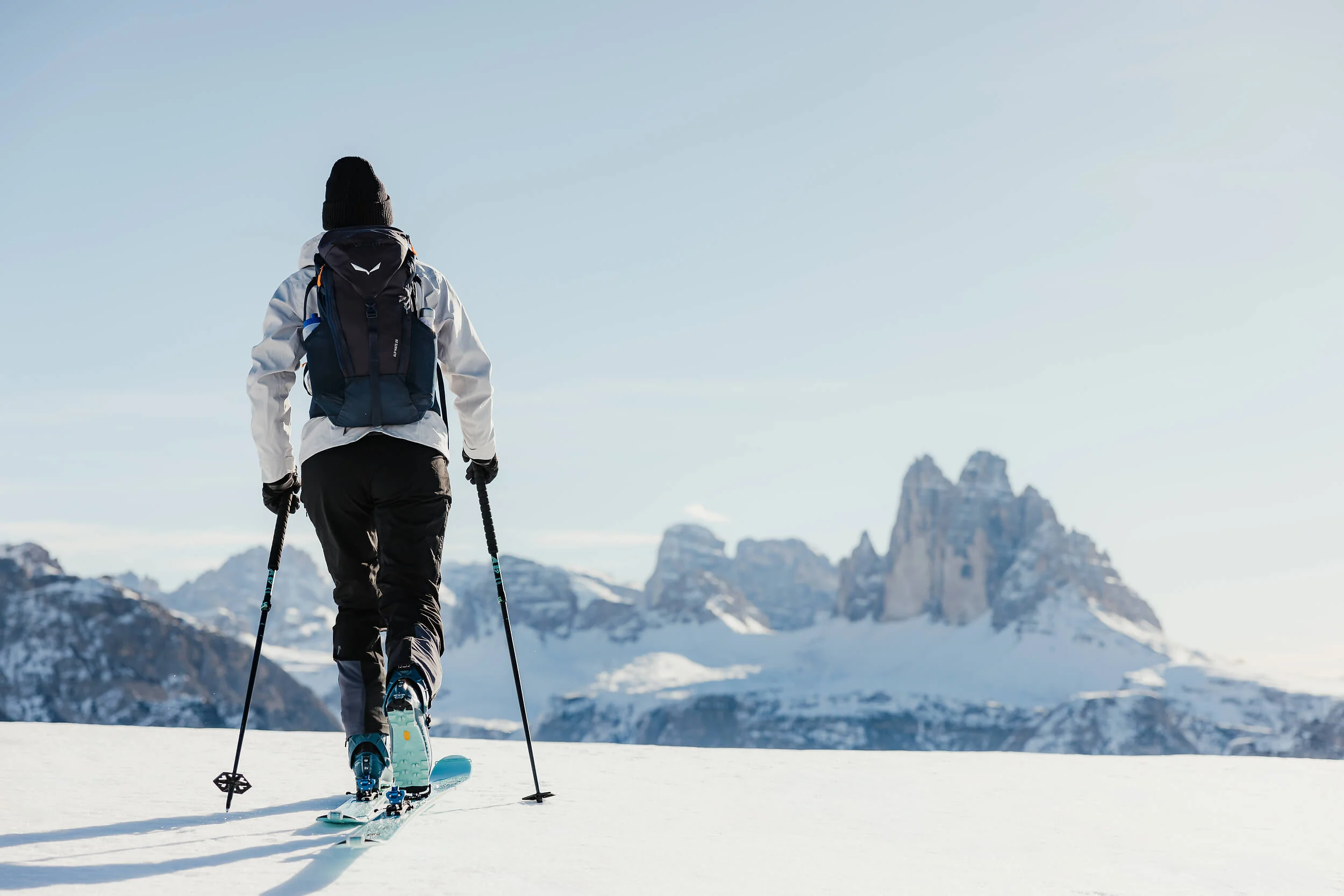 Skifahrer mit Rucksack auf verschneitem Berg vor Gipfeln