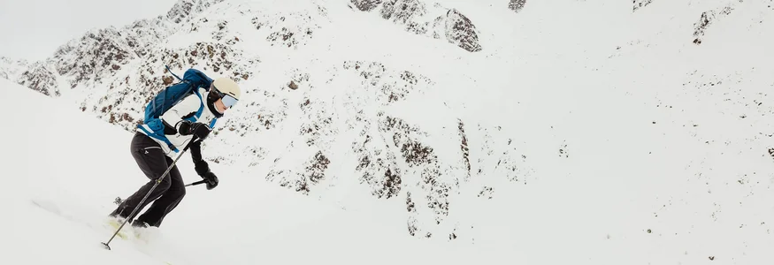 Skifahrer mit Rucksack fährt bergab in schneebedeckten Alpen