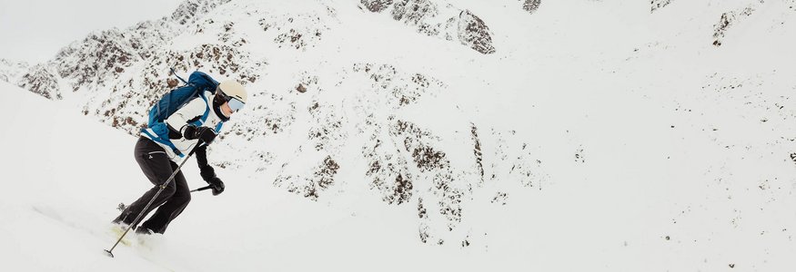 Skifahrer mit Rucksack fährt bergab in schneebedeckten Alpen