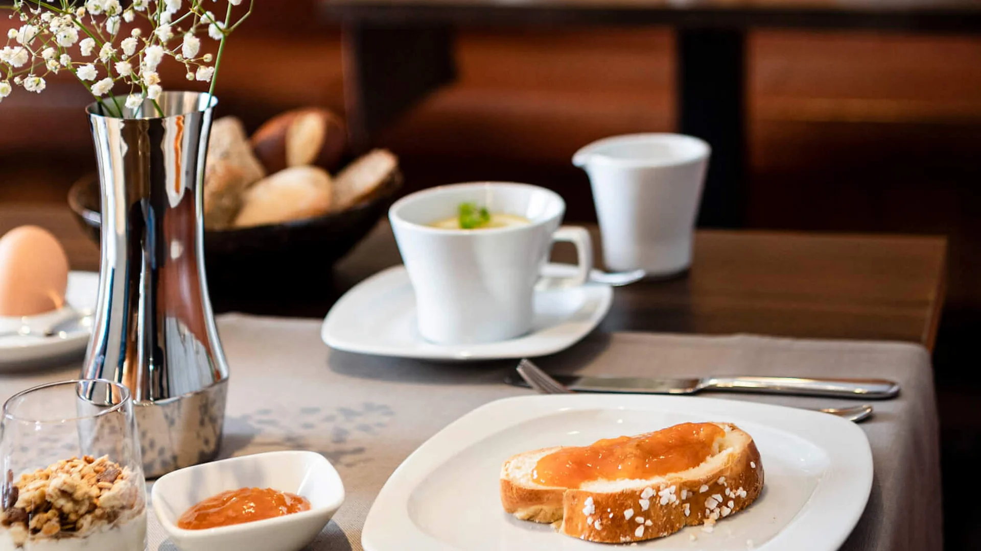 Frühstückstisch mit Toast, Marmelade, Kaffee und Blume im Restaurant