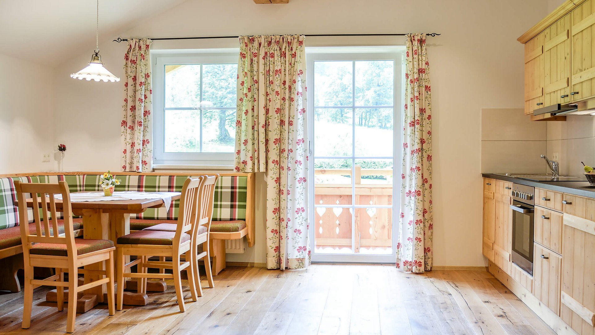 Bright kitchen with dining table, wooden chairs, and window with curtains