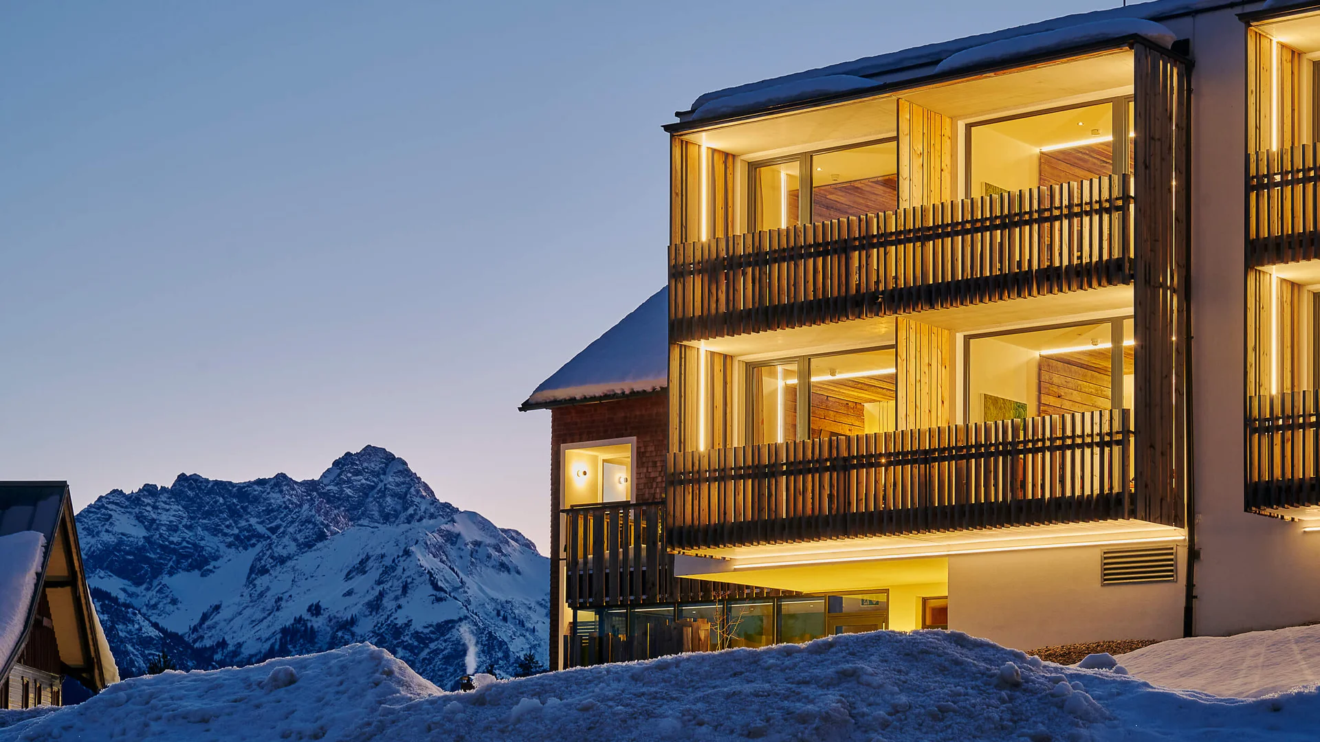 Genuss- und Aktivhotel Sonnenburg **** © Alexander Kaiser Beleuchtetes Gebäude mit Balkonen im Schnee vor verschneitem Berg bei Dämmerung