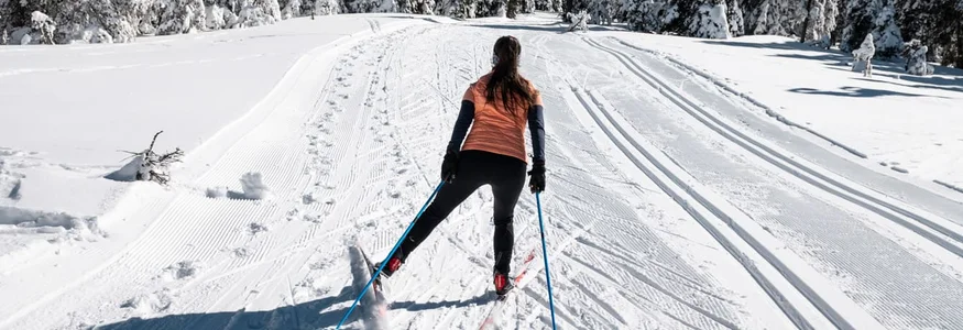 Slow Down in Slowenien © Daniel Hug Frau beim Skilanglauf auf verschneiter Winterlandschaft mit Tannenbäumen