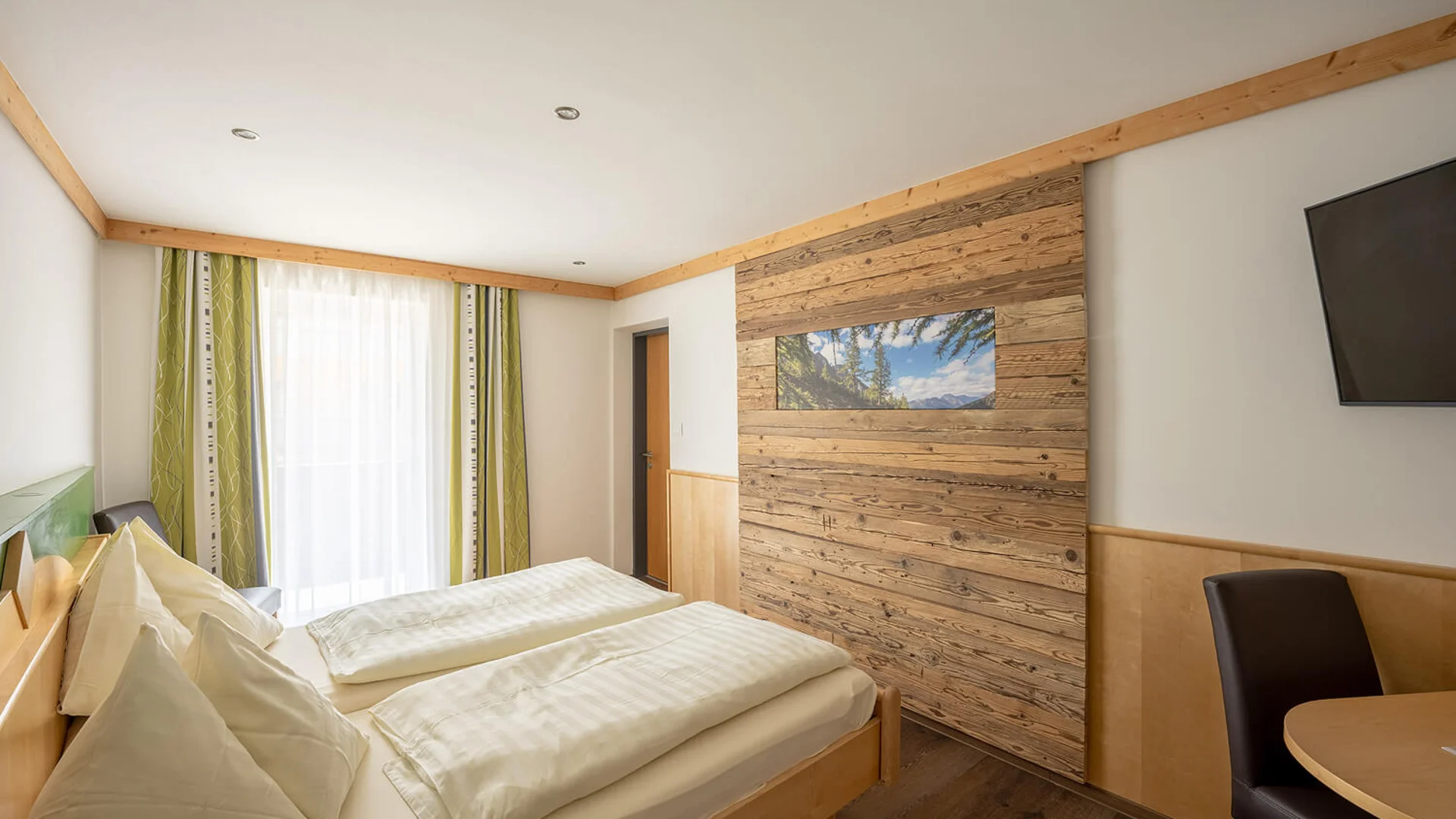 Hotel Eggerhof *** © Franz Gerdl Helles Schlafzimmer mit Doppelbett, Holzwand und Fenster mit Vorhängen