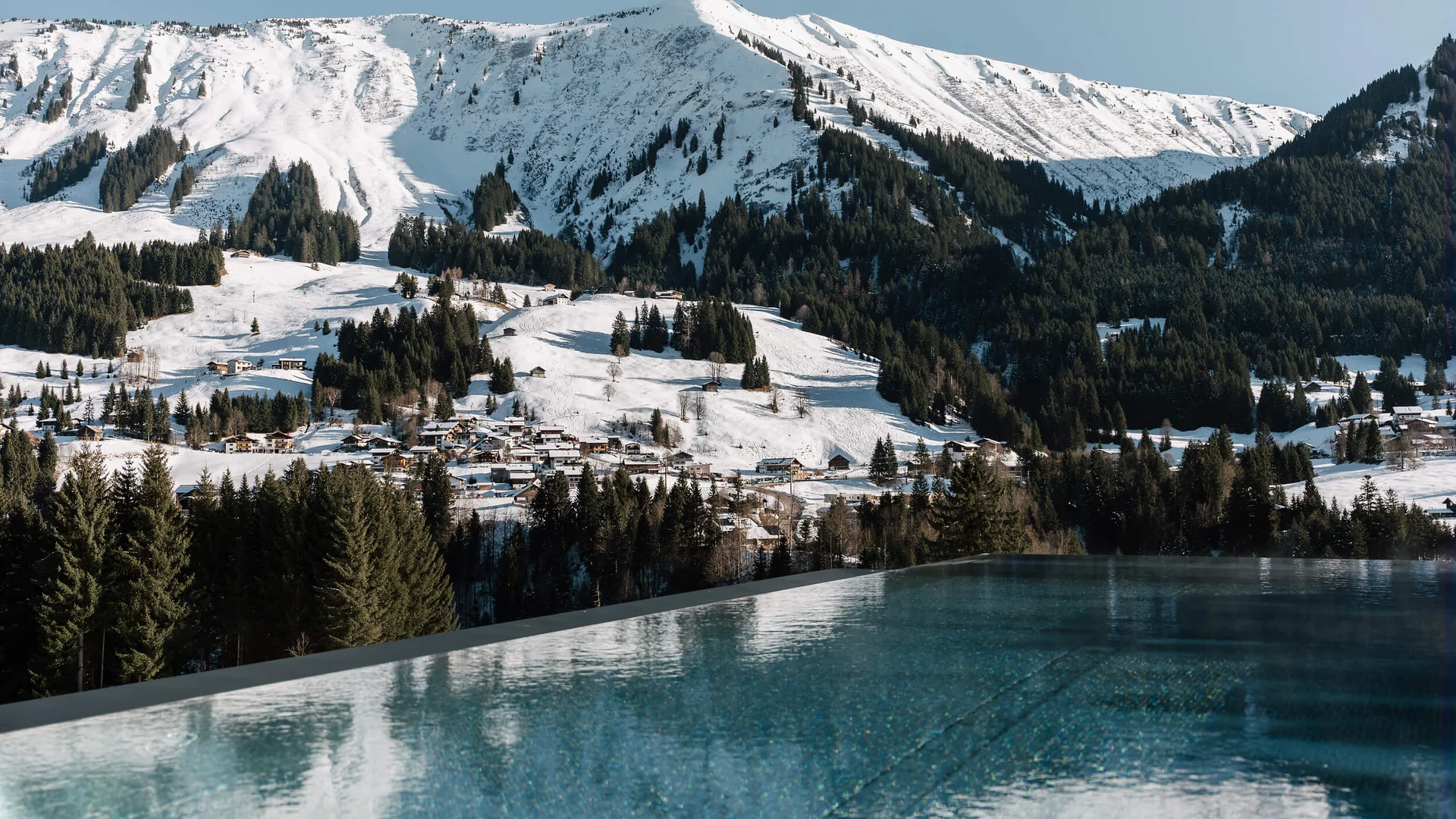 Genuss- und Aktivhotel Sonnenburg **** © Elisa Moosbrugger Verschneites Bergdorf und Berge hinter einem Außenpool