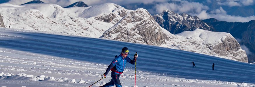 Skilangläufer trainiert auf schneebedecktem Berg mit Alpen im Hintergrund