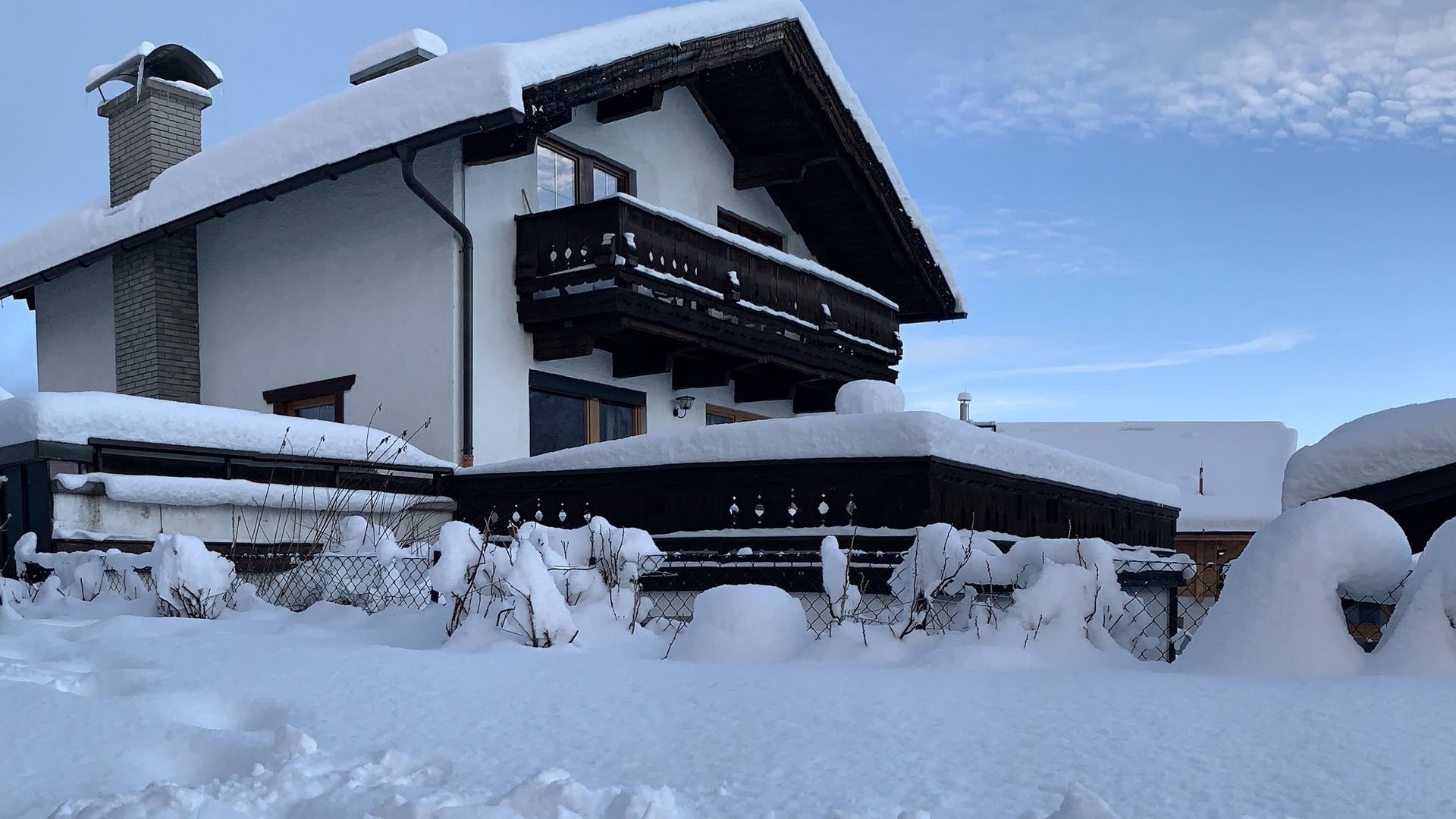 House and garden covered with snow under clear sky